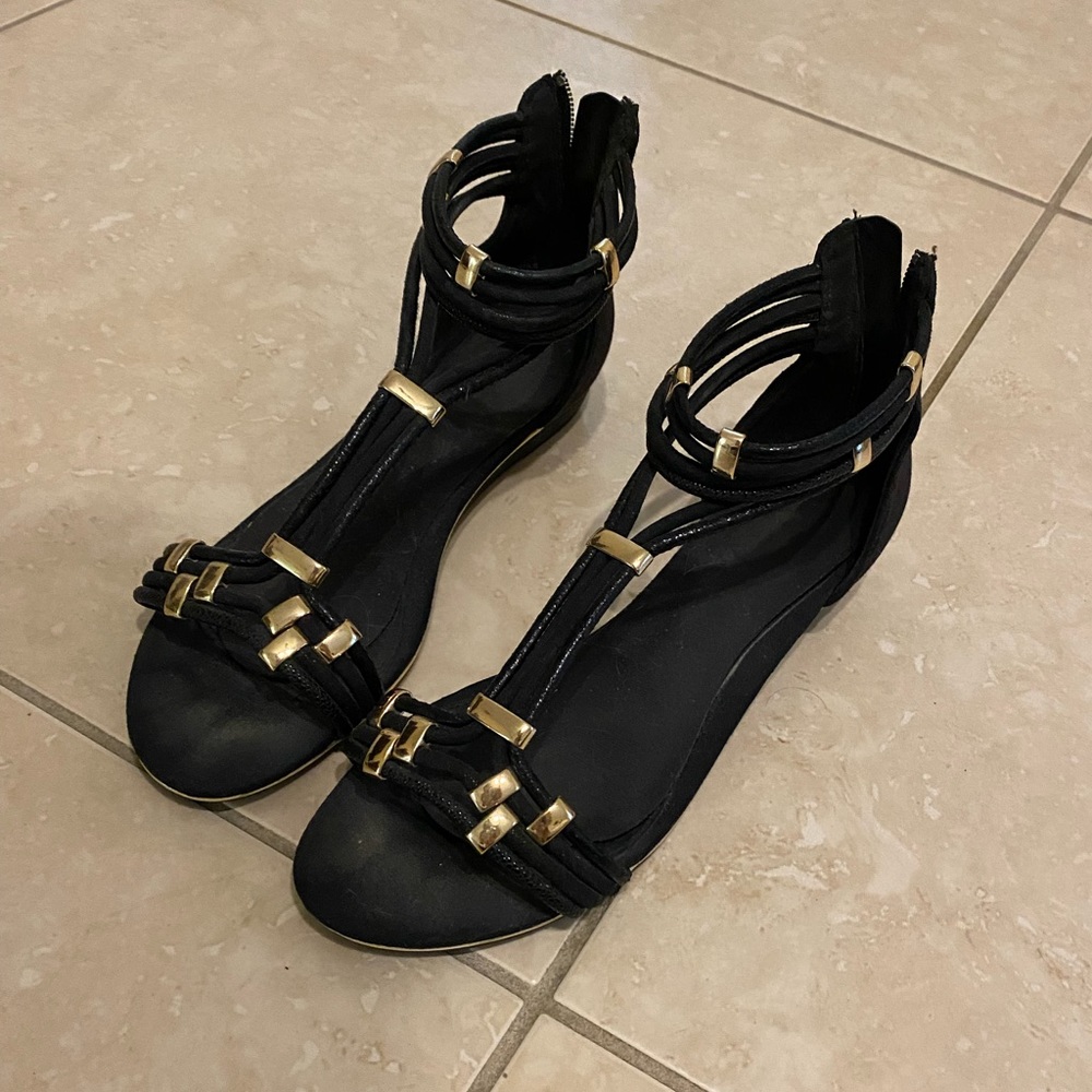Aldo Black wedge sandals featuring gold metal hardware accents.